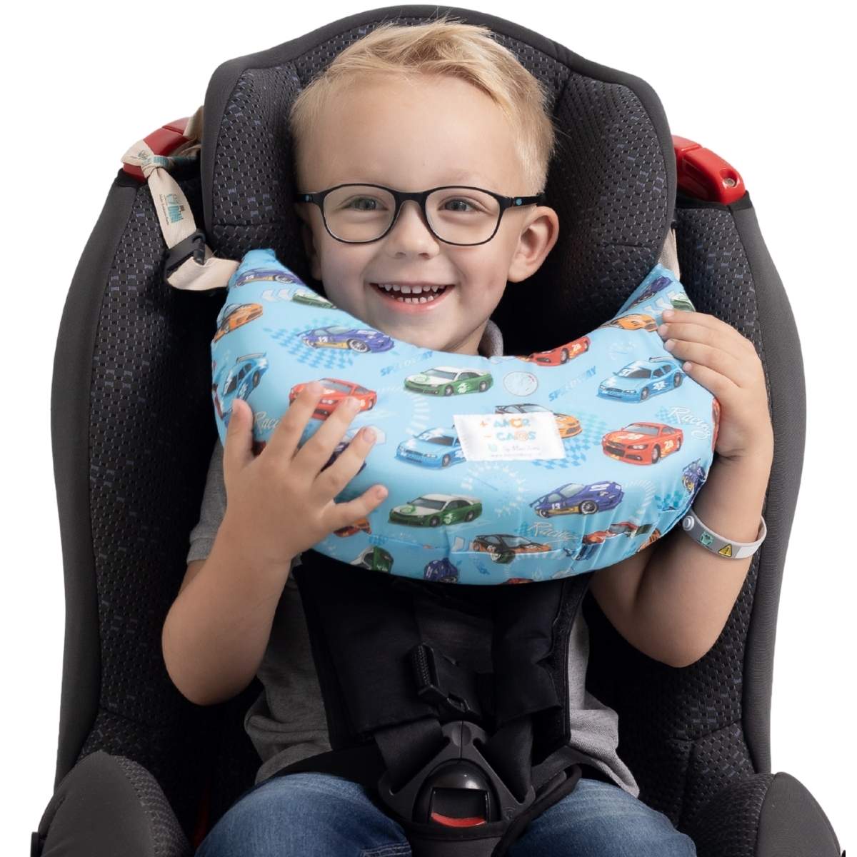 Menino sorrindo na cadeirinha com a almofada de pescoço Nanadini estampa carrinhos — apoio cervical confortável para crianças em viagens de carro