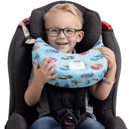 Menino sorrindo na cadeirinha com a almofada de pescoço Nanadini estampa carrinhos — apoio cervical confortável para crianças em viagens de carro